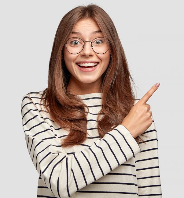 Horizontal shot of joyful pleased good looking youngster points at upper right corner with index finger, invites you go there, dressed in casual clothes, poses against white background, blank space